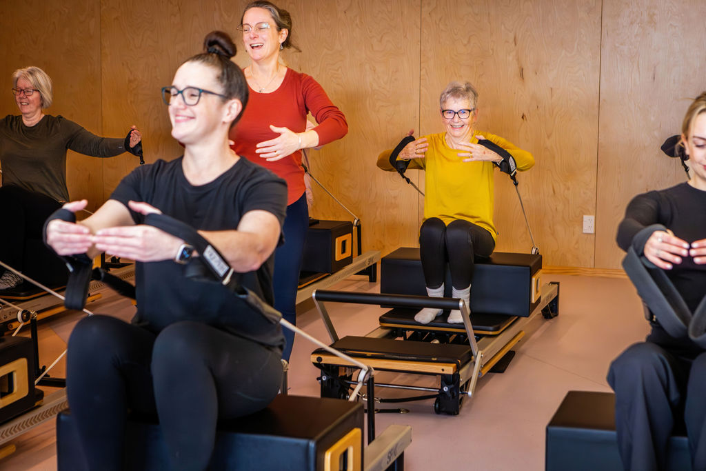 Smiling clients during a reformer class at Upside Pilates